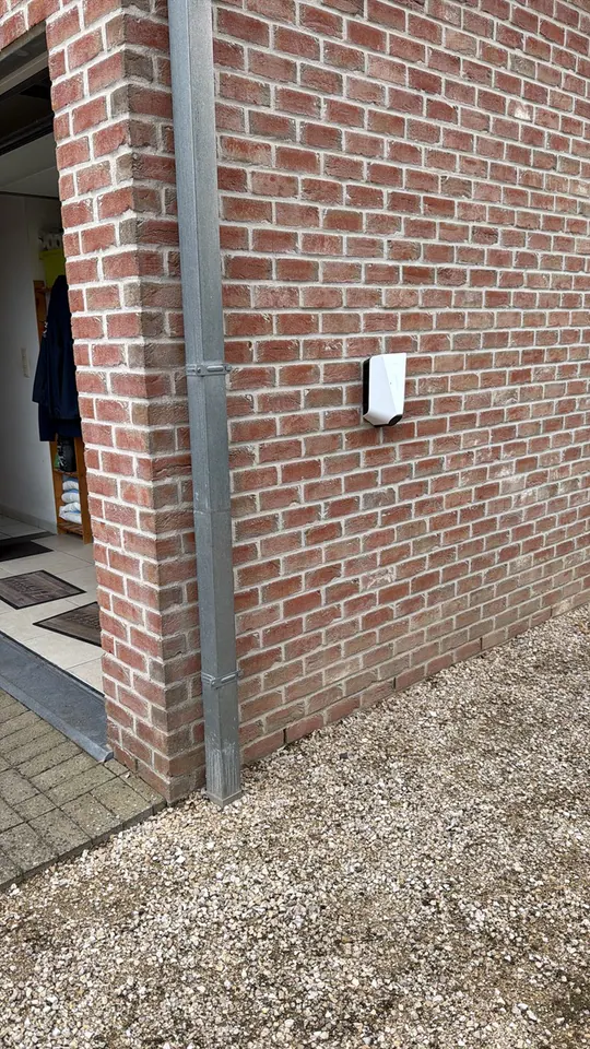 Witte Easee-lader aan een rode bakstenen buitenmuur, geplaatst door Laadnatie.