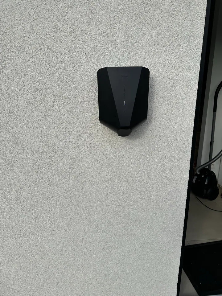 Zwarte Easee-lader aan een witte buitenmuur, geplaatst door Laadnatie.