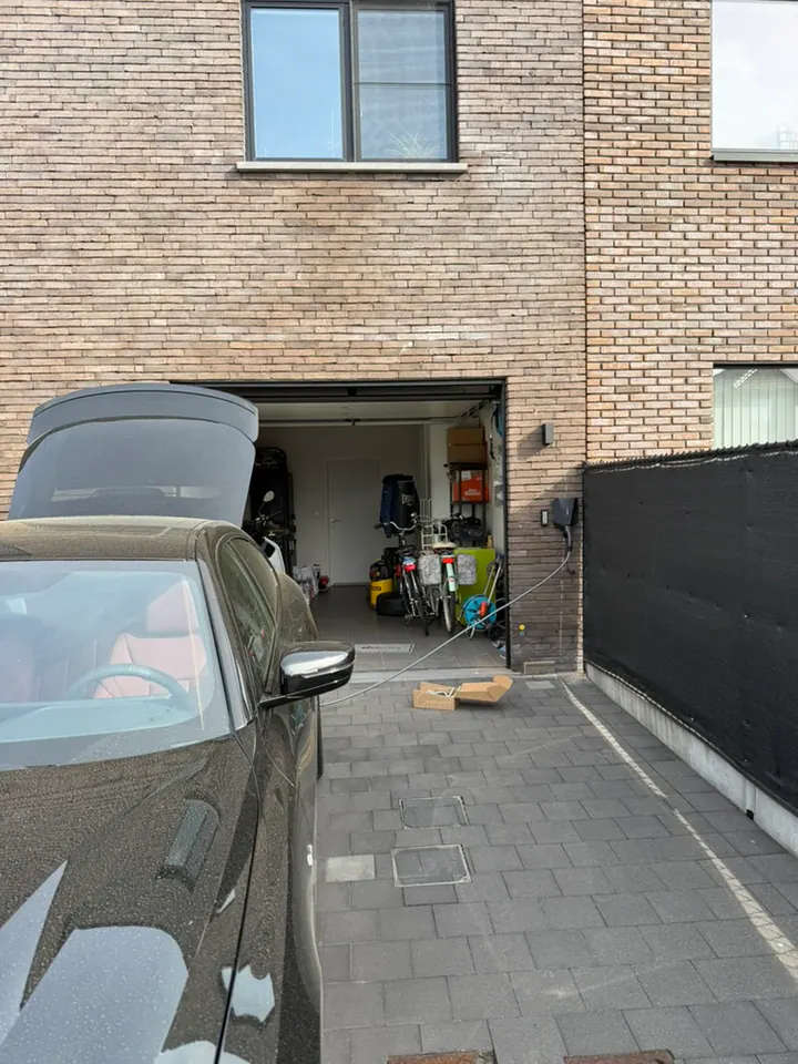Zwarte Easee-lader aan de gevel naast een garage, geplaatst door Laadnatie.