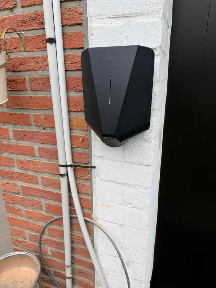 Zwarte Easee-lader aan een smalle witte buitenmuur, geplaatst door Laadnatie.