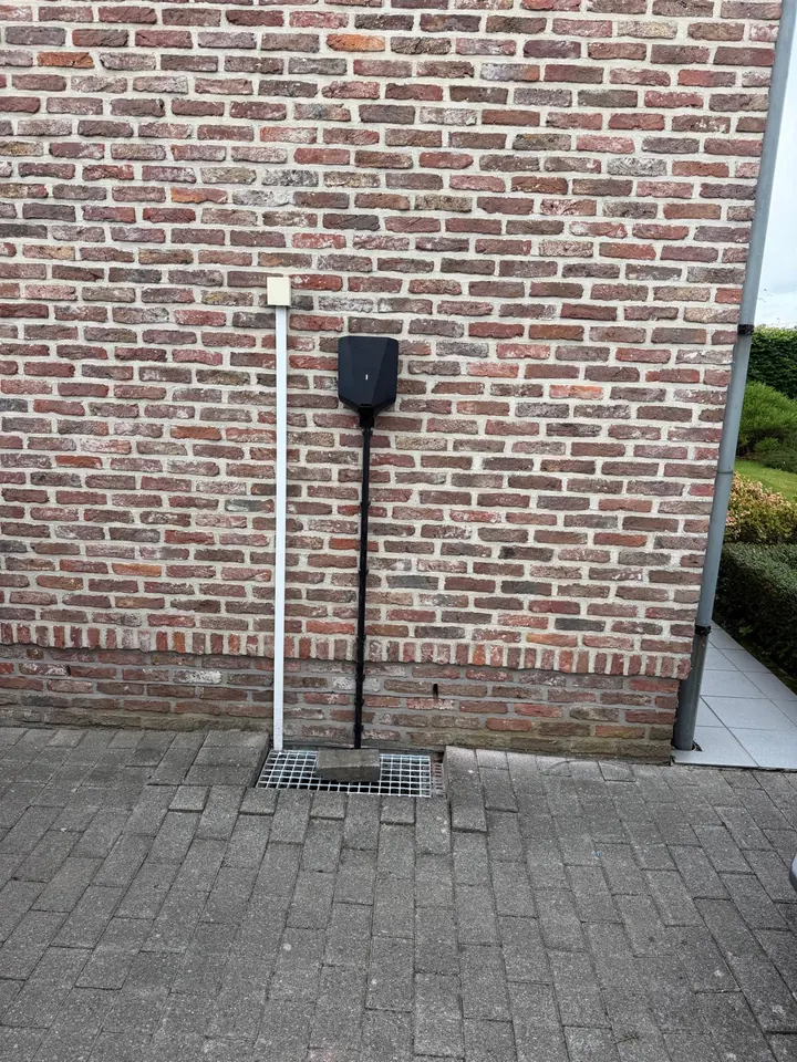 Zwarte Easee-lader aan een brede landelijke bakstenen gevel, geplaatst door Laadnatie.